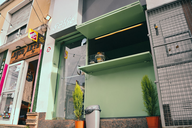 Fachada de Café Café en Alta Córdoba: muro verde sage, logo blanco y ventanal de atención al paso.